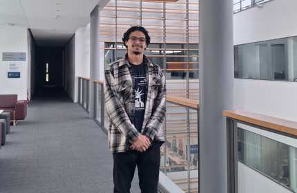 A man stands on a balcony in a bright atrium space.