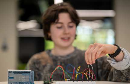 A person adjusts wires connected to a circuit board.