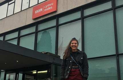 Sarah Bill stands outside the main entrance of the BBC Cymru Wales building