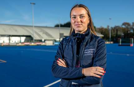 A woman in a blue jacket stands confidently on a tennis court.