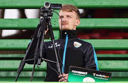 Connor Hindley, wearing a black tracksuit, looks through the lens of a mounted camcorder
