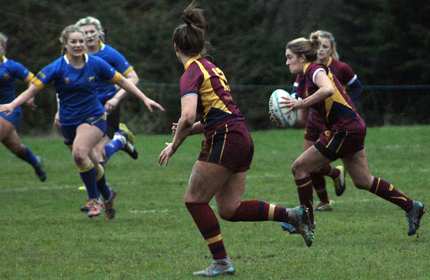 Ellyse Hopkins, right, holds a rugby ball and prepares to be tackled during a game of rugby