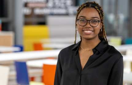 Headshot of Esperanca Antonio, wearing a black shirt and glasses