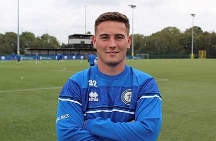 A man in a blue shirt stands confidently on a vibrant football field, ready for action.