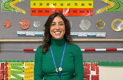 Hari Neumann stands in front of a numeracy classroom display