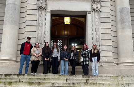 A group of University students stand for a photograph at the top of a set of stairs in front the entrance to Cardiff Crown Court