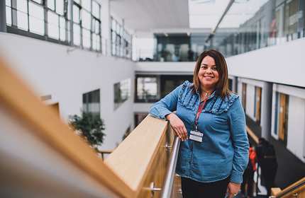 Woman in blue denim shirt stands on a staircase in the Cardiff School of Management