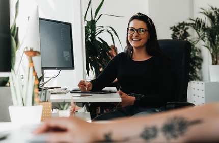 Woman sits at a desk working on an electronic tablet