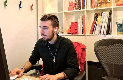 Man in a black short works on a desktop computer