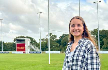 Llinos Morgan, wearing a striped shirt, stands on an outdoor rugby pitch