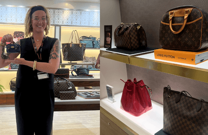 A woman holds a bag in front of a colorful display of various purses in a retail store.