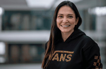 A woman wearing a black hoodie with bold gold lettering, presenting a modern and trendy look.
