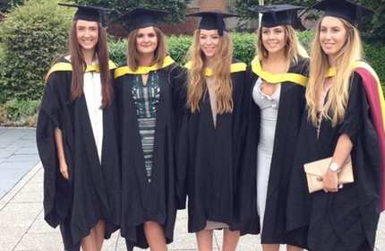Amy James stands with four other students all wearing the graduation gowns and caps