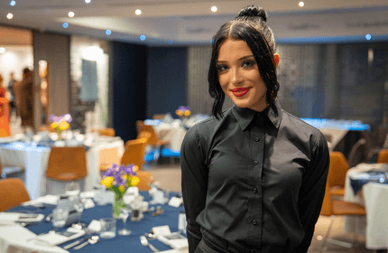 A young woman in a black shirt stands in a dining suite