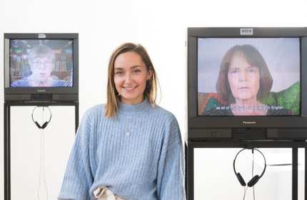 Gwenllian Llwyd stands between two CRT televisions on stands with a white background