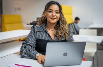 A young woman works on a laptop at a table