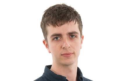 A headshot of a young man, wearing a blue polo shirt, in front of a white background
