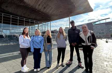 A group of people stand outside the the Senedd in Cardiff Bay.