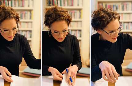 A person in a library turns the pages of a notebook.