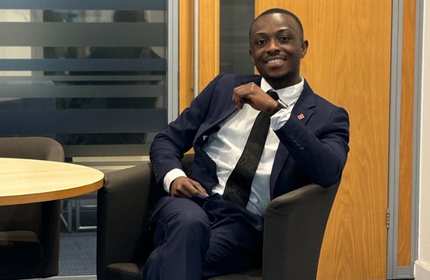 A person in a suit and tie sits at a chair next to a small round table.