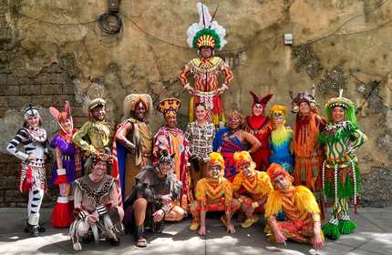 A diverse group of people in vibrant costumes, smiling and posing together for a group photo.