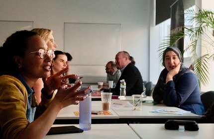 A diverse group of people engaged in conversation while seated around a table.
