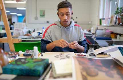 Student works on their art project while sat at a table