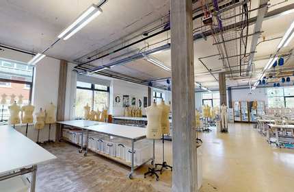 Rows of tables in a large room, with tailor's dummies and sewing machines