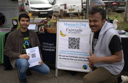 Two young men kneeling beside a Fairtrade information standee