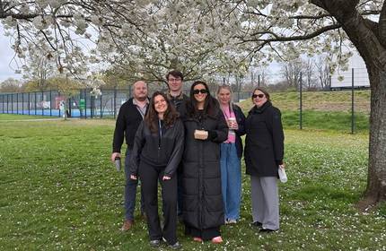 A small group of people stand below white flower trees