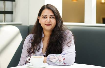 MSc Digital Marketing Management student sits at a table with a cup of coffee