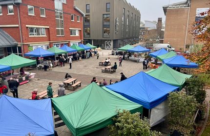 An aerial view of a large community market with tent stall in a quadrant