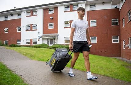 Student drags a rolling suitcase behind them on the Cyncoed campus