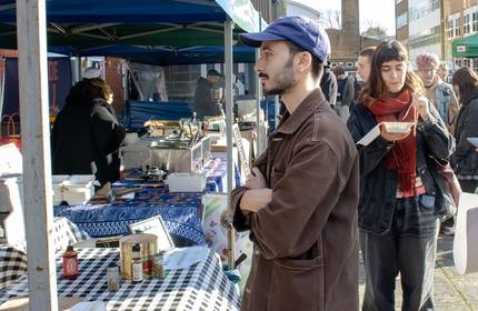 A young man looks at items for sale at a market stall
