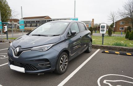 A grey Cardiff Met-branded car parked and charging on campus
