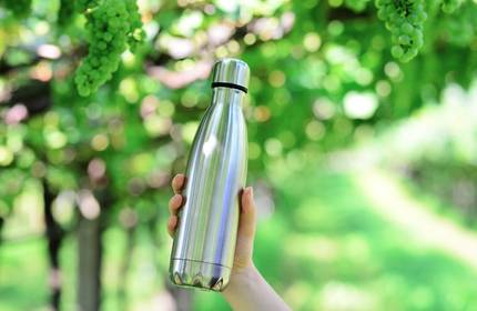 A reusable silver metallic bottle held up