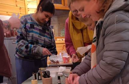 A small group of people work around a row of tables working on various coloured shampoos