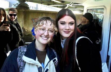Two young people lean in to one another to pose for a photograph
