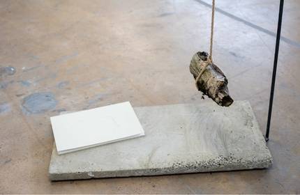 A piece of wood hangs above a slab of concrete