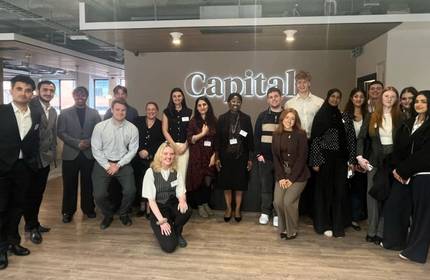 A large group of people pose in the office entrance of Capital Law