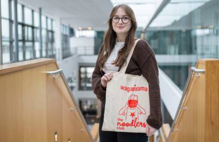 A woman proudly displays a tote bag that reads, 