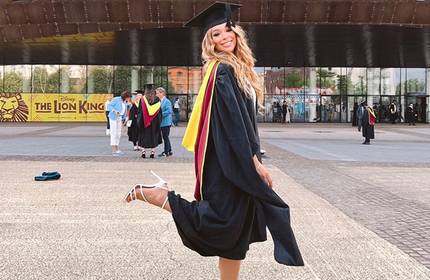 Elianna Chavez poses for a photograph wearing their graduate cap and gown outside the Cardiff Millennium Centre during Graduation