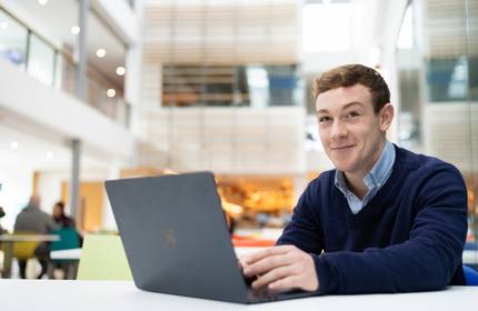 James Charles-White sits at a desk working from a laptop
