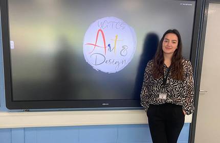 Maia White, stands in front of an electronic display board