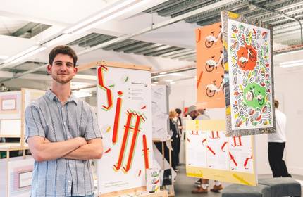 A man stands in front of a colourful display of various posters, examining the artwork and information presented.