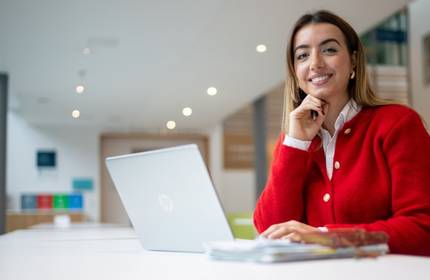 Xhevilta Rizani sits at a long desk in front of a laptop and writing pad