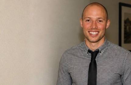 A man in a shirt and tie smiles at the camera