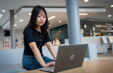 A young woman focuses on a laptop she is working on