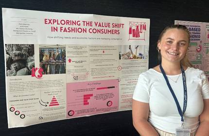 A young woman in a white t-shirt stands in front of an information display