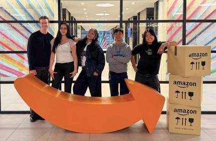 A group of people stand alongside Amazon-themed merchandise